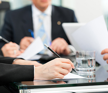 Business professionals reviewing and signing documents at a meeting.